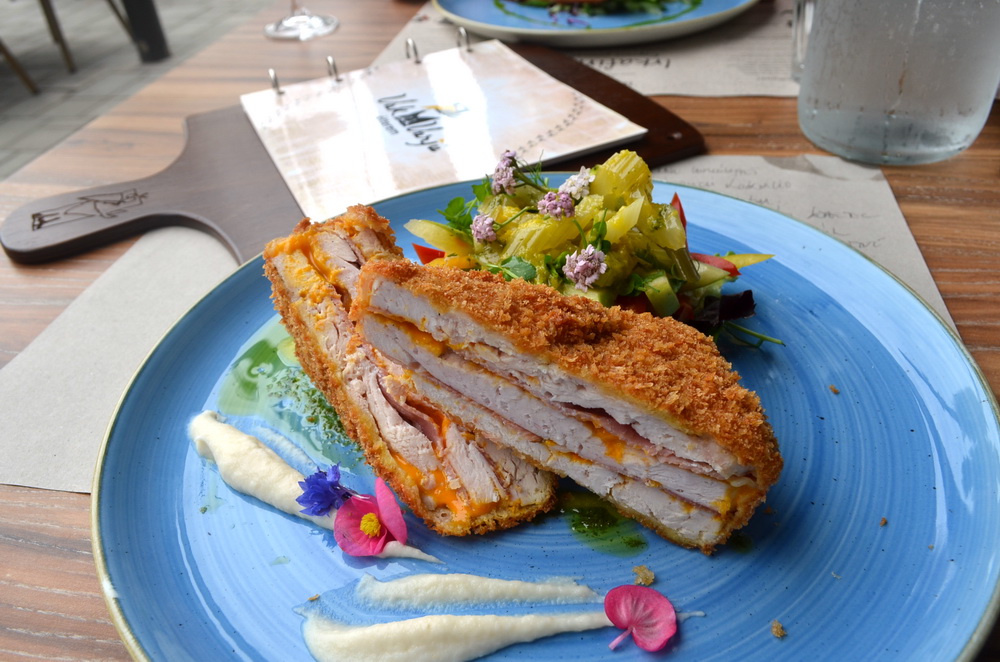 Cheddar sajttal töltött csirkemell érlelt sonkával, paszternákpürével és friss salátákkal a VakVarjú Csónakház éttermében. GasztroMagazin 2018.